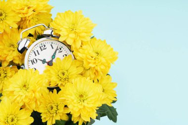 Sarı çiçeklerle çevrili çalar saat.