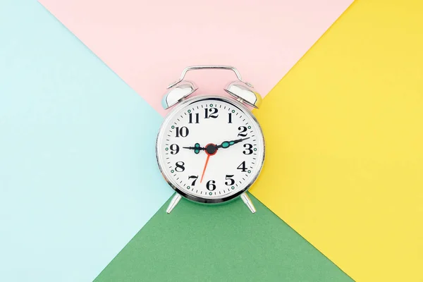 Reloj despertador sobre fondo de papel colorido — Foto de Stock