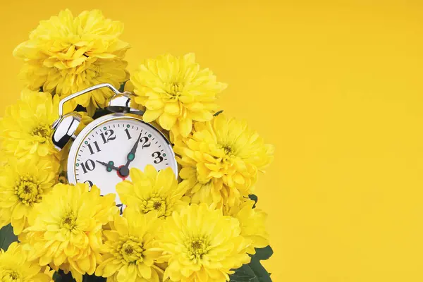 Reloj despertador rodeado de flores amarillas — Foto de Stock