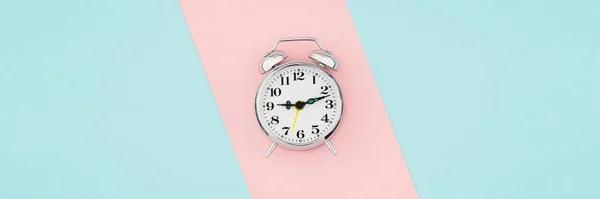 Reloj despertador sobre fondo de papel rosa azul — Foto de Stock