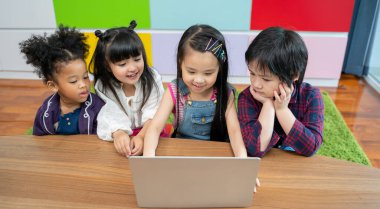 Dizüstü bilgisayarda film izleyen bir grup çocuk. Evde dizüstü bilgisayarla oynayan çocuklar