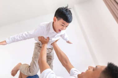 Mutlu baba evdeki yatakta yatarken oğluyla oynuyor.