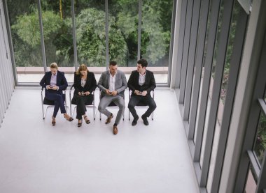 İş adamları akıllı telefon kullanıyor ve doğa yeşili ofis sandalyesinde birbirlerini yiyorlar.