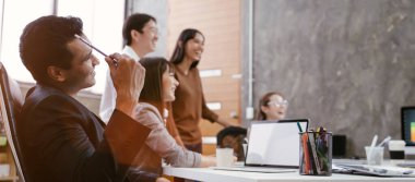Asyalı iş adamlarından oluşan bir grup modern ofiste toplanıyor tasarım planlama ve fikir kavramı üzerinde çalışıyorlar.