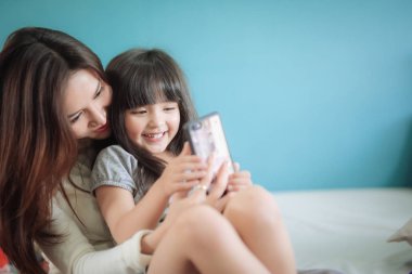 Portre Mutlu Kız annesiyle akıllı telefon oynuyor.