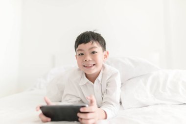 Yatak odasında akıllı telefonu olan çocuk..