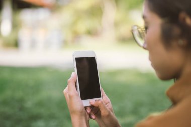 Parkta cep telefonunu kullanan bir kız