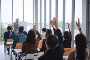 Seminer sınıfındaki büyük bir grubun ellerini ve kollarını kaldırıp konferans seminer salonunda konuşmacı ile aynı fikirde oldular.