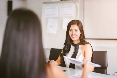 İş kadını ofisteki müdüre belgeyi uzatıyor. Ofis çalışanı, başkana yapılan işle ilgili bir rapor sunuyor..