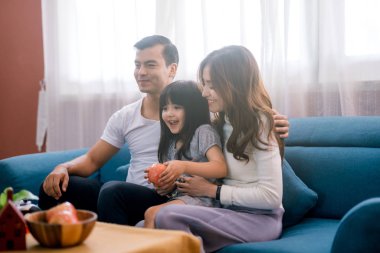 Mutlu bir aile kanepede birlikte televizyon izliyor.