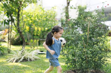 Doğa parkında küçük bir kız. Sevimli çocuk futbol oynuyor.