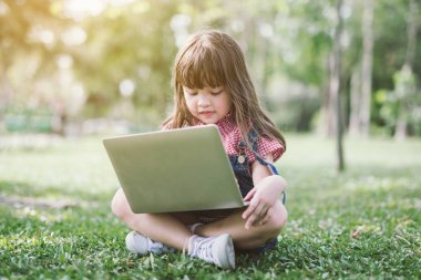Dizüstü bilgisayarı olan küçük kız. Mutlu çocuklar doğa teknolojisi eğitim kavramında