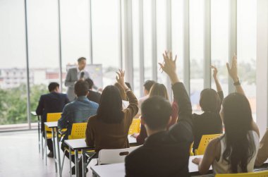 Seminer sınıfındaki büyük bir grubun ellerini ve kollarını kaldırıp konferans seminer salonunda konuşmacı ile aynı fikirde oldular. 