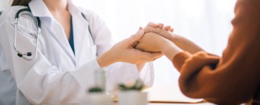 Doktor kadın hastasının güvenini tazelediği için elini tutuyor..