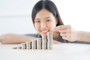 Genç Asyalı kadın para yığını yapıyor. Yatırım kaydet finans kavramı.