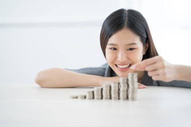 Genç Asyalı kadın para yığını yapıyor. Yatırım kaydet finans kavramı.
