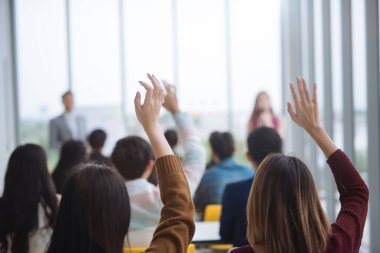Seminer sınıfındaki büyük bir grubun ellerini ve kollarını kaldırıp konferans seminer salonunda konuşmacı ile aynı fikirde oldular.