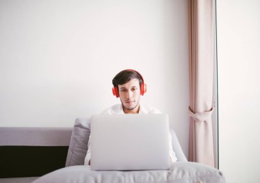 Dizüstü bilgisayar kullanan bir adam, koltukta oturuyor.