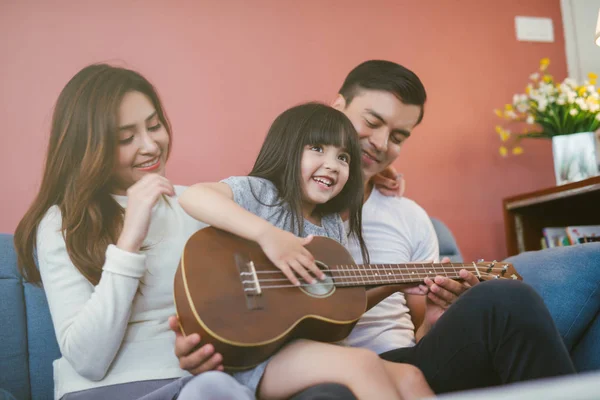 Evde gitarlı mutlu bir aile. Ebeveyn kızı gitar çalarken görüyor 