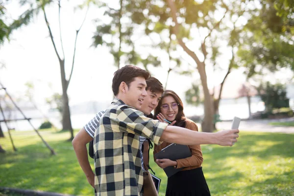 Parktaki arkadaşlar akıllı telefonlar kullanarak selfie çekiyorlar.