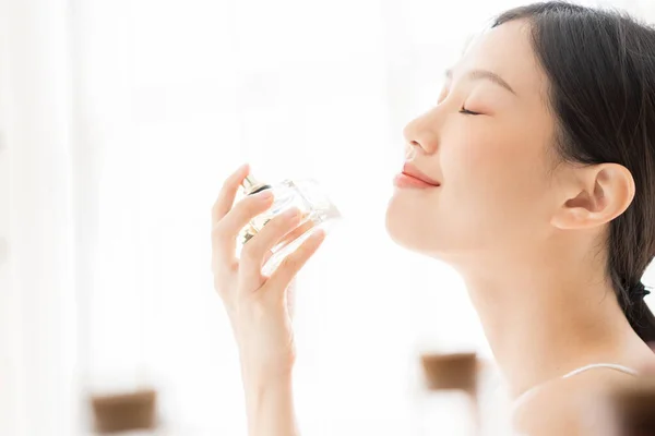 Asian girl with perfume, young woman applying perfume on her wrist and  smelling