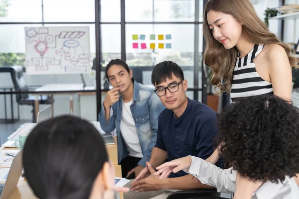 Bir grup Asyalı iş adamı modern ofiste toplanıyor. Fikir planlama ve paylaşma konsepti üzerinde çalışıyorlar.