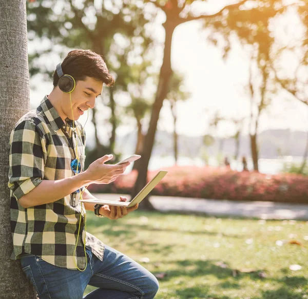 Manlig Student Avkopplande Och Lyssnar Musik Sitter Gräset Stadsparken — Stockfoto