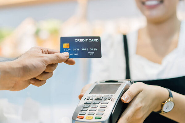 клиент в кафе платит кредитной картой продавцу
