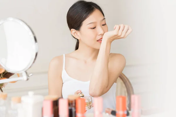 Asian girl with perfume, young woman applying perfume on her wrist and  smelling