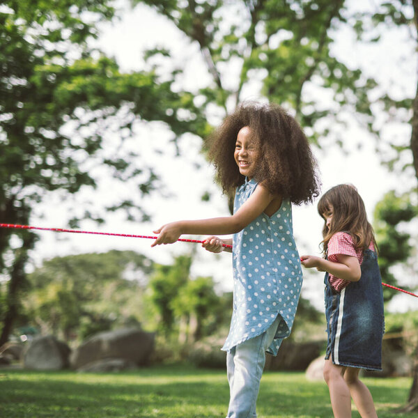 Happy children playing tug of war at the park