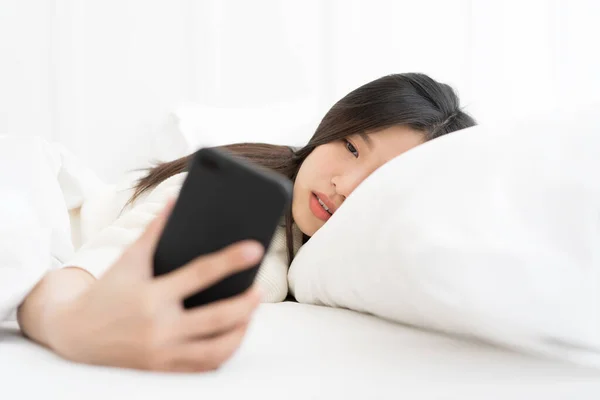 Asian Woman woke up by smartphone alarm clock and turning off snoozing phone alarm clock