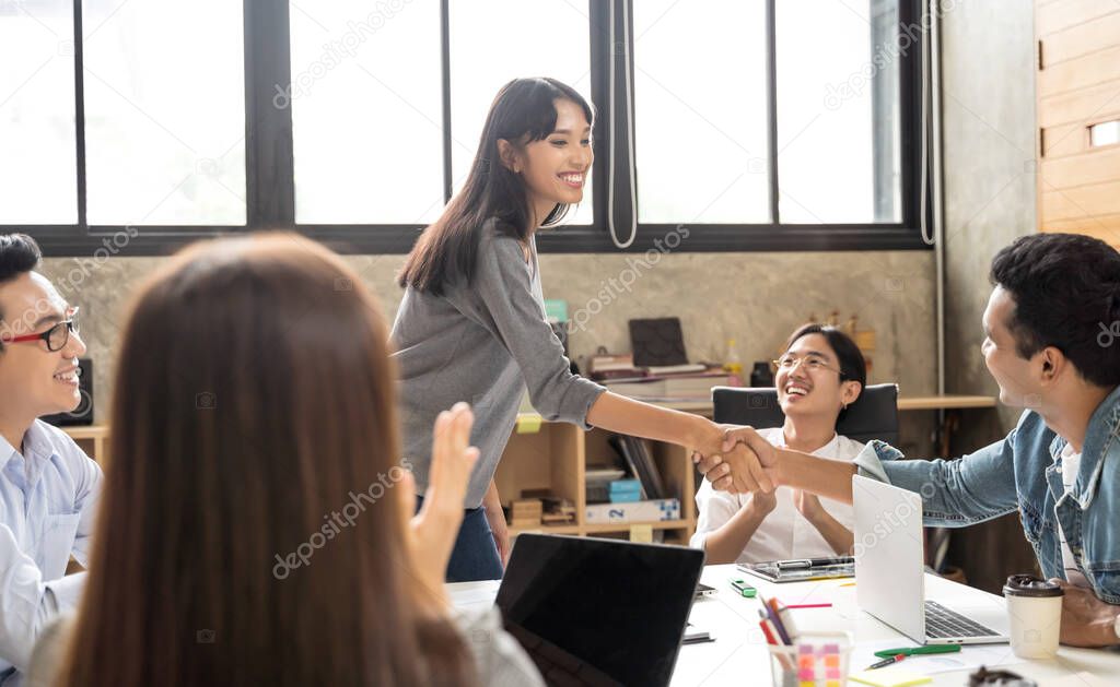 Asian business people smart casual wear shaking hands while working in the creative office. Business team creative concept