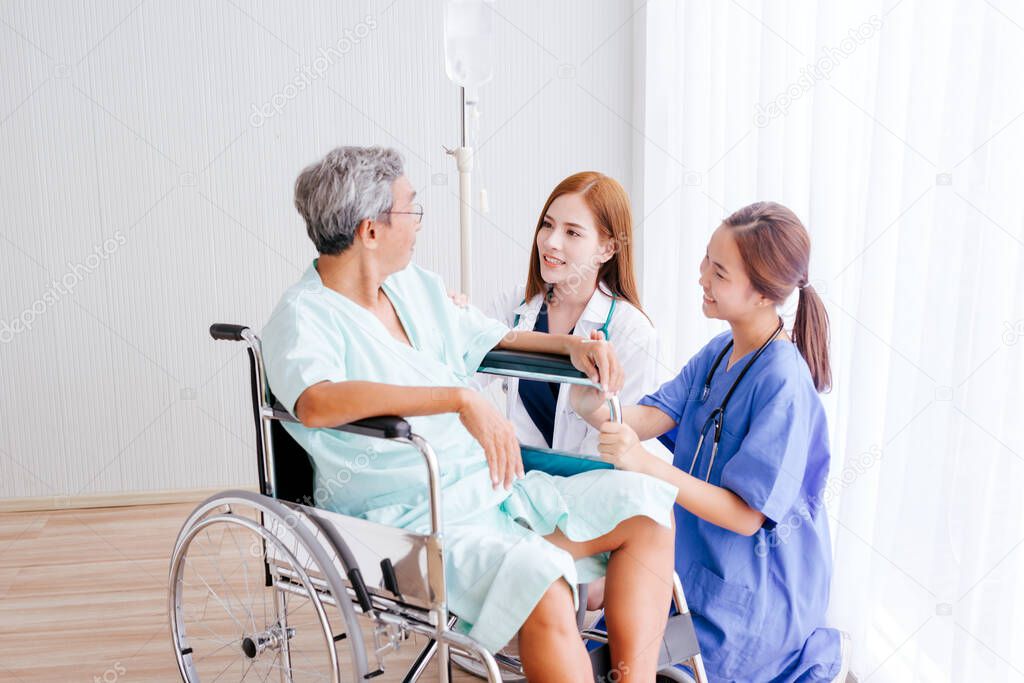Beautiful Asian doctor and nurse taking care of senior patient in wheelchair