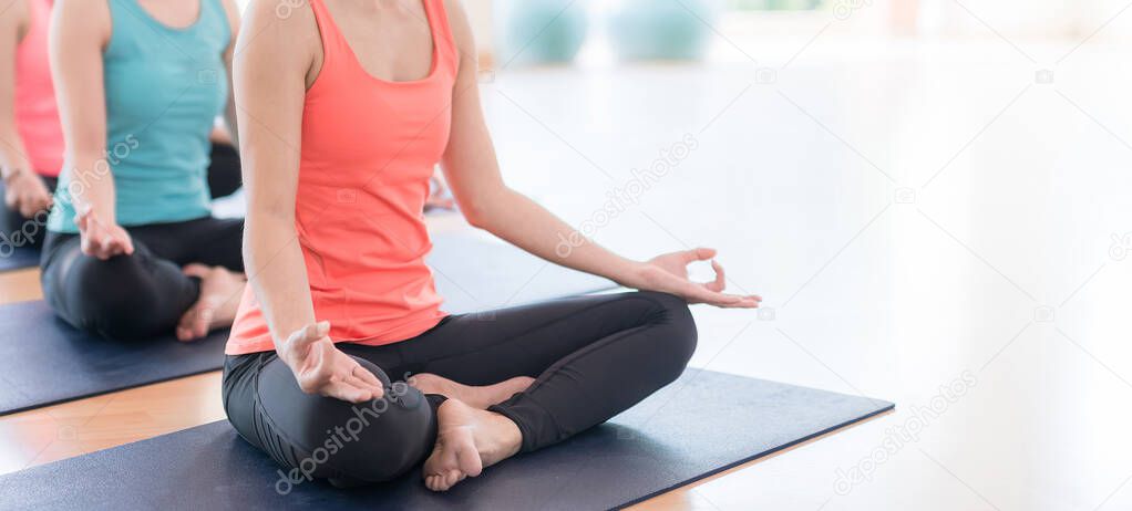 Attractive young Asian woman group exercising and sitting in yoga lotus position in yoga classes