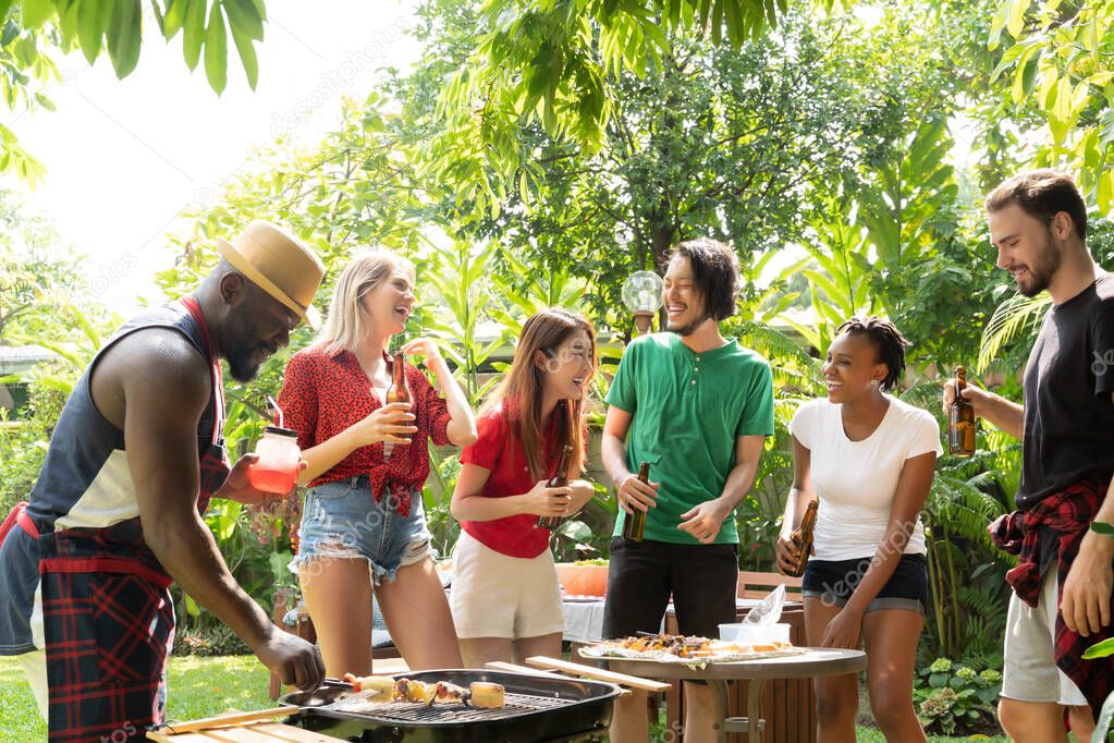 Group of people toasting beers celebration and having barbecue party outdoors garden