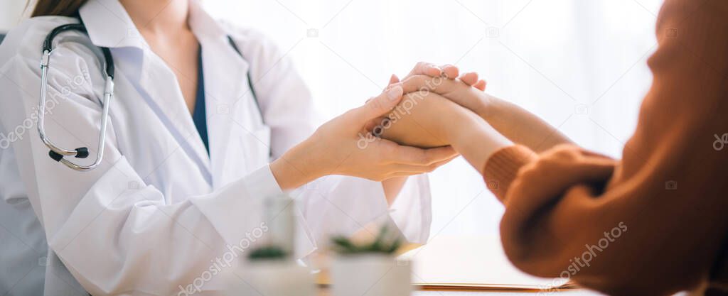 Doctor woman holding hand for reassuring her female patient.