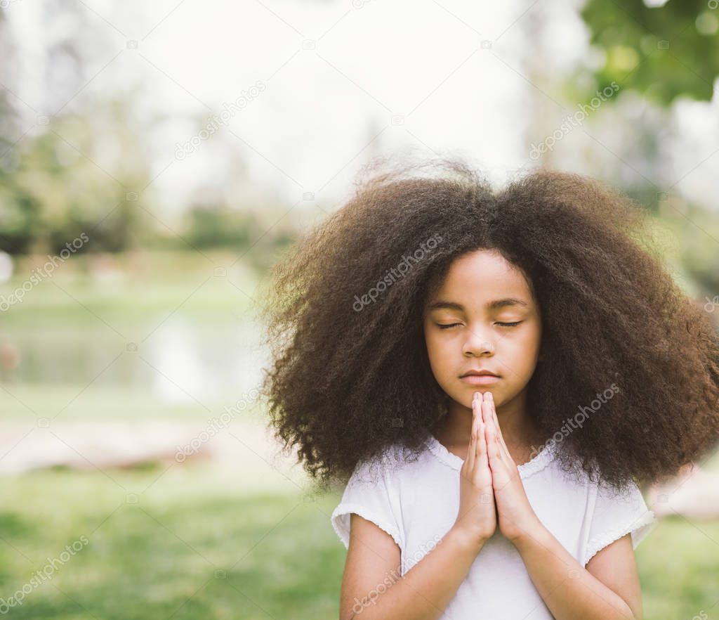 Afro child praying. Black kid prays. Gesture of faith.Hands folded in prayer concept for faith,spirituality and religion