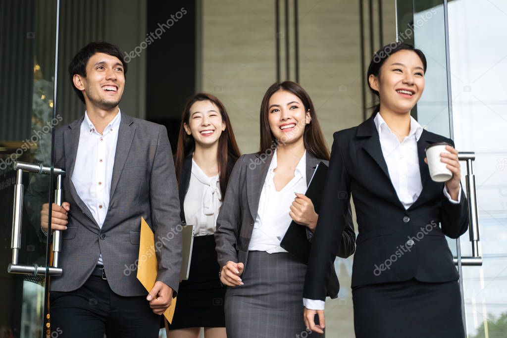 Asian business people walking to go out office building. Young businessman and businesswoman talking and Open the office door.