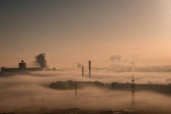 misty morning over the industrial area of the city, chimneys and smoke over factories