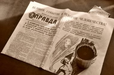 Masadaki sahnede Yuri Gagarin 'in uzaya uçuşuyla ilgili ana haberleri veren ilk kişi. Masanın üzerinde Gürcistan çayı ve sigarası olan bir bardak var..