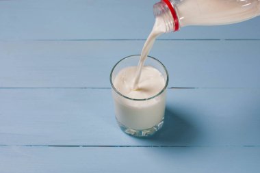 Bir şişe süt bir cam kabı dökülür. Bir cam ahşap mavi kurullarında standları