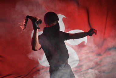 Yüzünde bandaj olan bir adam Hong Kong bayrağının arka planına yanan bir şişe fırlatıyor. Stüdyo fotoğrafçılığı. Sokak protestoları teması