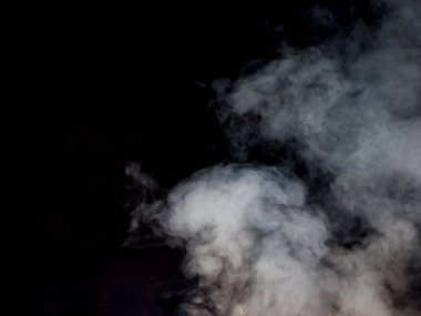 Hafif duman koyu bir arka planda dökülür ve akar. Stüdyo fotoğrafçılık