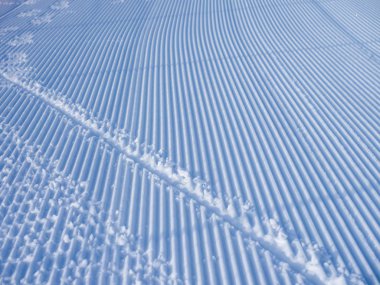 Karda kar aracı izleri var. Çizgiler inanılmaz karlı bir doku oluşturuyor. Bir kayak merkezinde rahatlama teması