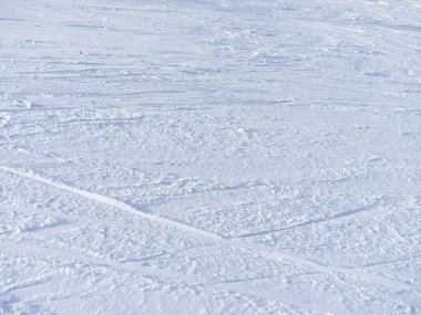 Karlı bir doku. Yüzeyde birçok kayakçı izi var. Kış günü