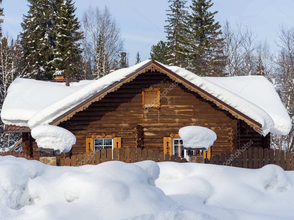 Wooden house in the forest. Winter day in the Siberian taiga. Wooden stylish fence