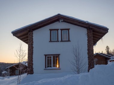 Gornaya Salanga kayak merkezinde Alp tarzı bir otel. Güneş doğuyor. Güzel sabah ışığı