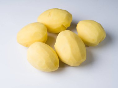 Beyaz bir yüzeyde birkaç soyulmuş patates. Yemek hazırlığı. Stüdyo fotoğrafçılık