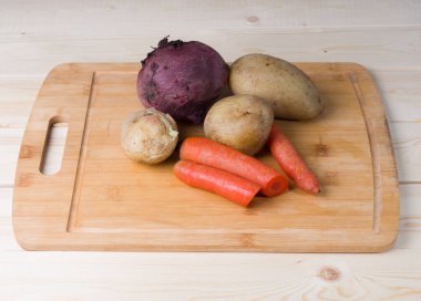 Ahşap kesme tahtasında haşlanmış sebzeler. Pancar, havuç ve patates. Daha fazla pişirmek için yarı bitmiş ürünler. Yan görünüm