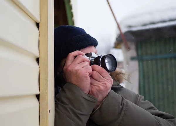 A man takes pictures. A man in the winter on the street took aim with a camera. Photographer at work